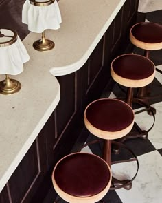 three stools sitting on top of a checkered floor in front of a counter