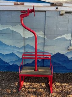 a red metal chair sitting in front of a wall