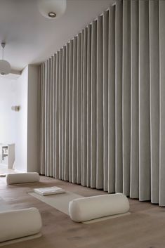 an empty room with large vertical blinds on the wall and white furniture in the foreground