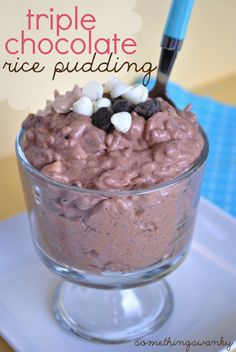 a glass bowl filled with chocolate pudding and marshmallows on top of a white plate