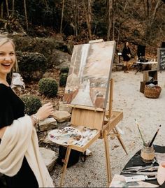 a woman standing in front of an easel painting