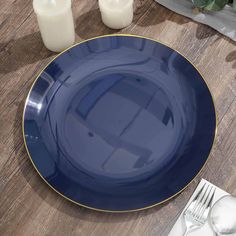 a blue plate sitting on top of a wooden table next to white candles and flowers