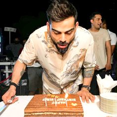 a man blowing out the candles on a cake that is sitting on top of a table