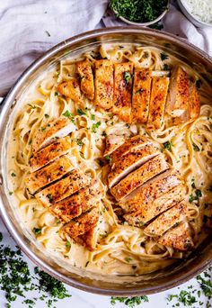 chicken alfredo with parmesan cheese in a pan on top of a white table