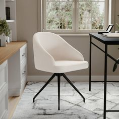 a white chair sitting in front of a window next to a desk with a laptop on it