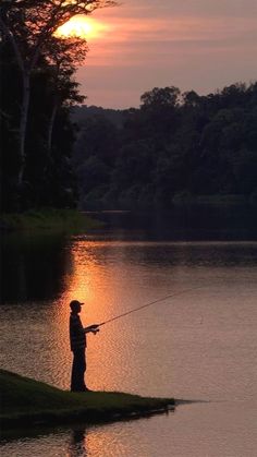 a man standing on the edge of a lake while fishing