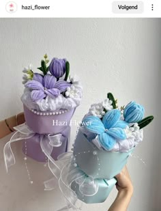 two vases that have flowers in them on top of each other, one is purple and the other is blue