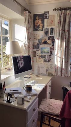 a desk with a computer on top of it next to a window filled with pictures