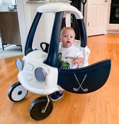 a baby sitting in a golf cart on the floor next to a table and chair