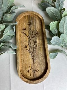 a wooden tray with flowers on it and leaves around the edge that says hope in cursive writing