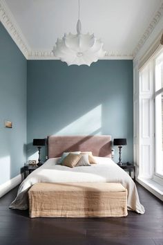 a bedroom with blue walls and white trim, hardwood flooring and a large bed