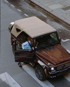 a car with a covered top driving down a street next to a sidewalk and traffic light