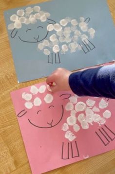 a child's hand is drawing sheep on paper