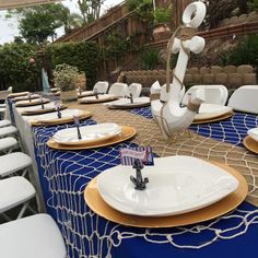 there are many white and gold plates on the table set up for an outdoor event