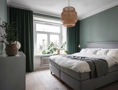 a bedroom with green walls, white bedding and wooden floors is pictured in this image