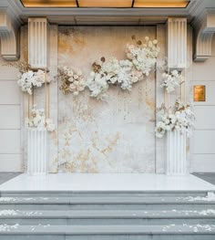 an outdoor wedding ceremony with white flowers on the wall and steps leading up to it