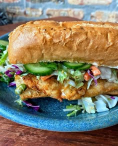 a sandwich with lettuce, cucumber and chicken on a blue plate