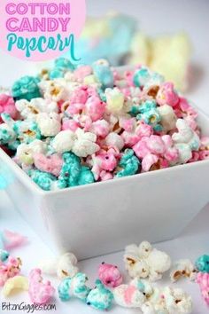 a white bowl filled with colorful popcorn on top of a blue and pink table cloth