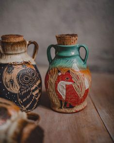 two ceramic vases with designs on them sitting on a table next to each other