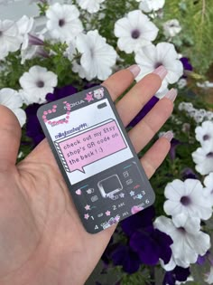 a person holding a cell phone in their left hand with flowers behind it and texting on the screen