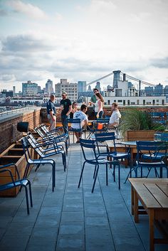 people are sitting at tables on top of a building with the city in the background