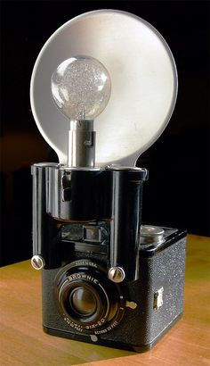 an old fashioned camera with a satellite dish on it's top, sitting on a wooden table