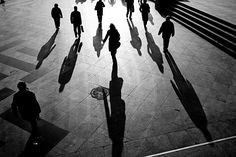 many people are walking down the street with their shadows on the ground