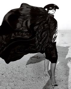 a woman in black dress and hat holding a large black cloth