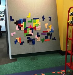 an office cubicle with colorful sticky notes on the wall and a red ladder next to it