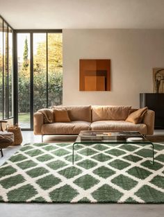 a living room filled with furniture and a green rug on top of a hard wood floor