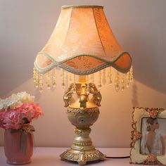 a lamp that is sitting on a table next to a vase with flowers in it