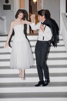 a man in a tuxedo and a woman in a white dress dance on steps