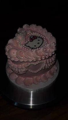 a hello kitty cake with pink icing and pearls on it's top, sitting on a silver plate