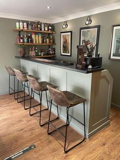 a bar with four stools in front of it and several shelves on the wall