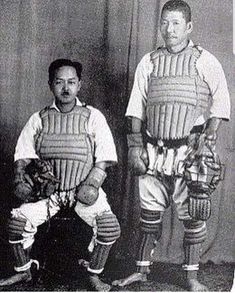 two men in baseball uniforms standing next to each other with bats and gloves on their hands