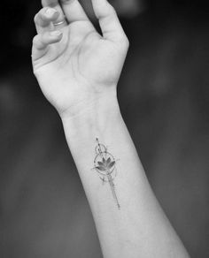 a small tattoo on the wrist of a woman's hand, with a flower