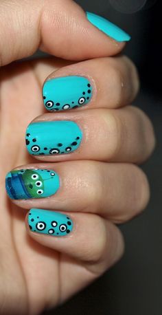 a woman's hand with blue nail polish and octopus design on it, holding up her