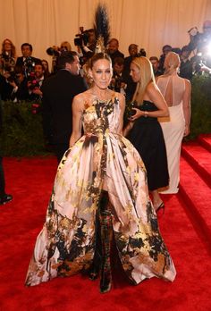 a woman in a floral dress standing on a red carpet