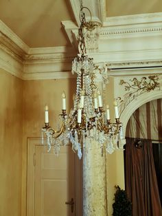 a chandelier hanging from the ceiling in a room with beige walls and curtains