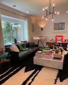 a living room filled with furniture and a large window next to a black rug on top of a hard wood floor