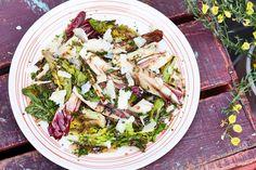 a white plate topped with salad on top of a wooden table