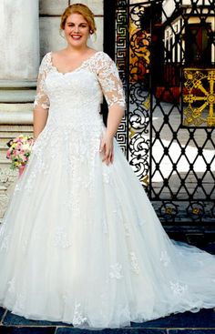 a woman standing in front of a gate wearing a wedding dress