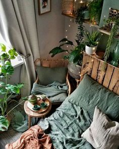 a bedroom with plants and blankets on the bed, next to a window that is lit by string lights