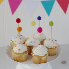 cupcakes with white frosting and colorful sprinkles are on a cake plate