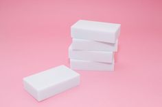 three white blocks of foam sitting on top of each other in front of a pink background