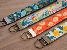 three key fobs are lined up on a wooden surface, one is orange and the other is green