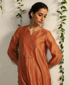 Editor's Note The timelessness of nature inspired motifs is interpreted through hand embroidered leaf motifs in this orange relaxed fit kurta set. The decadence is enhanced with our intricate nakshi and zari work. A beautiful nakshi work organza cut-out chanderi dupatta and scalloped edged narrow pants lend a glamorous touch to the overall look Fabric: Kurta: chanderi, pant: cotton satin, dupatta: organza Color: Orange Component: Kurta, pant and dupatta Occasion: Festive Note: Product colour may Satin Dupatta, Simple Kurtis, Chudidhar Neck Designs, Kurta And Dupatta, Embroidered Leaf, Girlfriends Day, Chanderi Dupatta, Kurta Patterns, Simple Kurta Designs