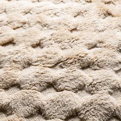 a close up view of the texture of a sheepskin rug in beige and white