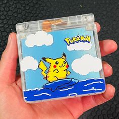 a hand holding a nintendo game case with a pikachu on it