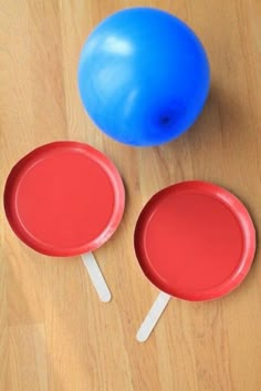 two ping pong paddles sitting on top of a wooden table next to a blue ball